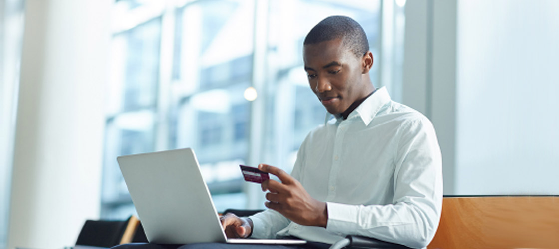 Business man with laptop looking at his business credit card to make online payment