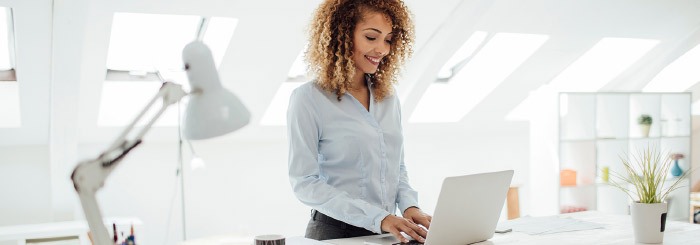 Smiling small business owner looking at her laptop to make online payment Smiling small business owner looking at her laptop to make online payment