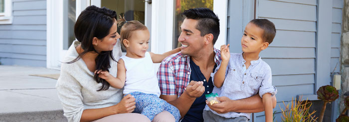 Happy family sitting in front of their home Happy family sitting in front of their home