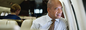 Optimistic business man looking out airplane window on international flight