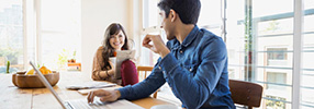Smiling couple looking at each other while online banking 