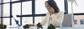 Smiling small business owner on her mobile phone and laptop for cash management services 