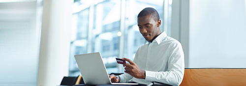 Business man with laptop looking at his business credit card to make online payment