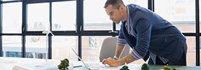 Small business owner looking at his laptop for cash management services 