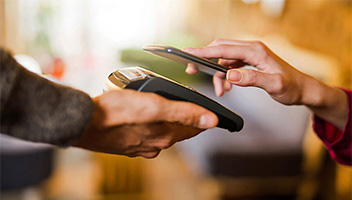 Hand holding credit card terminal and another hand holding mobile phone to pay and tap Hand holding credit card terminal and another hand holding mobile phone to pay and tap