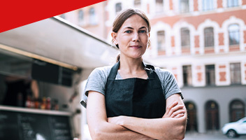 Confident female chef standing by food truck in city. Confident female chef standing by food truck in city.